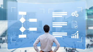 Man standing in front of a translucent blue holographic dashboard displaying a flowchart, text blocks, and icons.